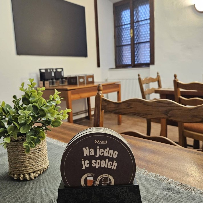 Nový interiér restaurace s pivními tácky Kozel a rostlinou na stole